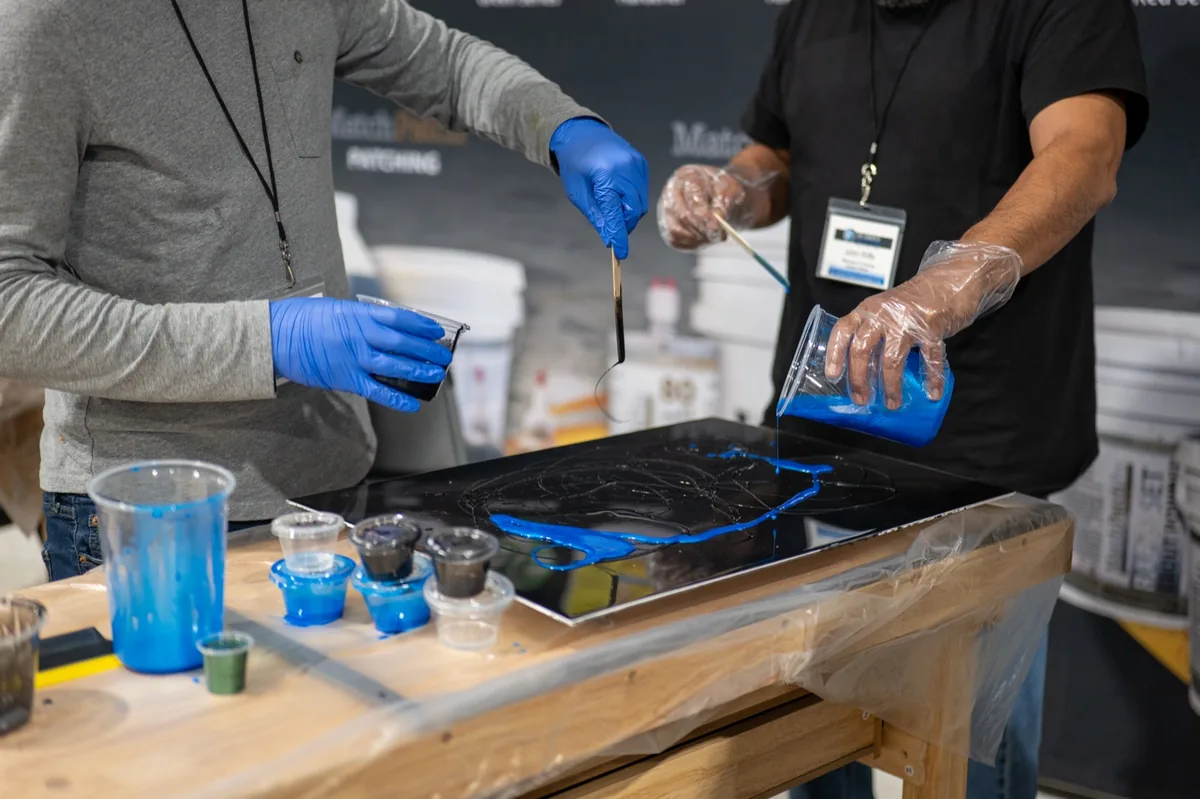 Installers pouring blue resin onto a panel during a hands-on training event
